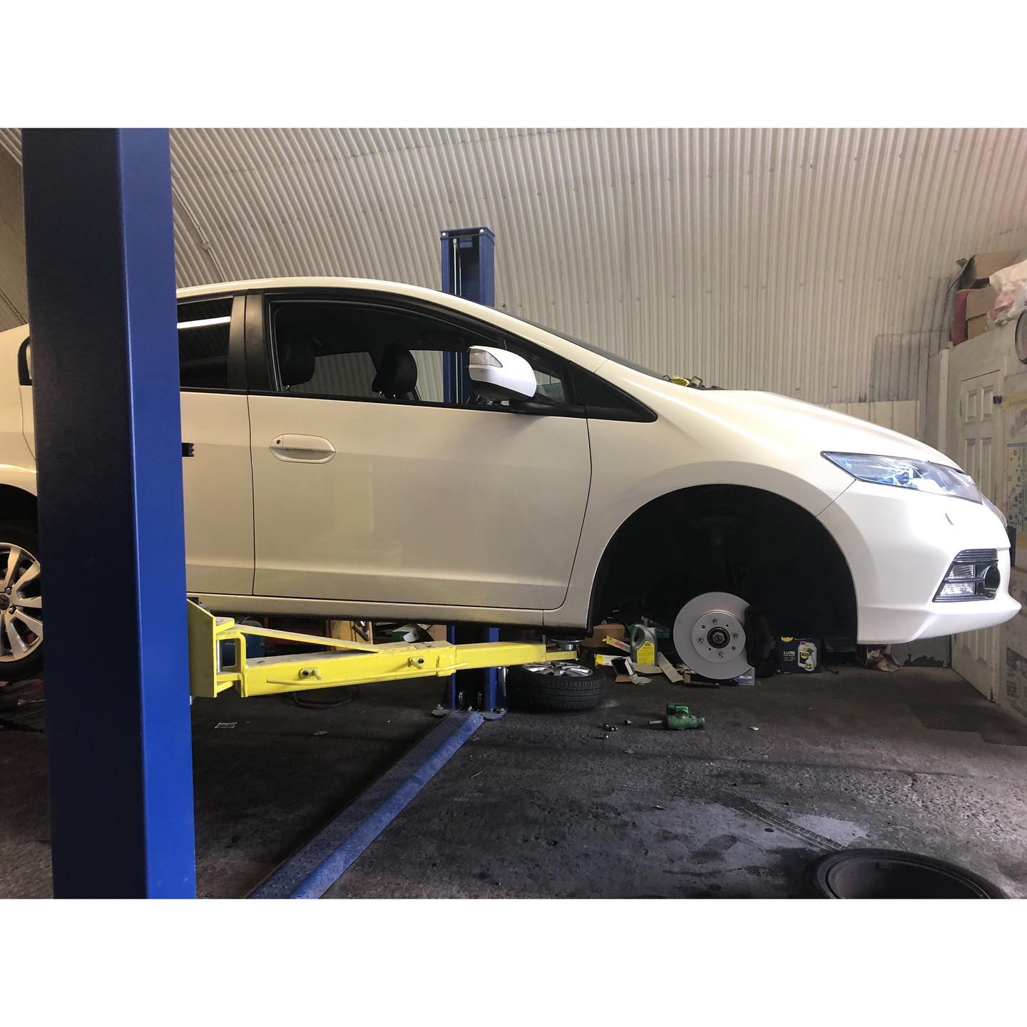White Honda Insight on the lift mid-service at ADE Auto Repairs