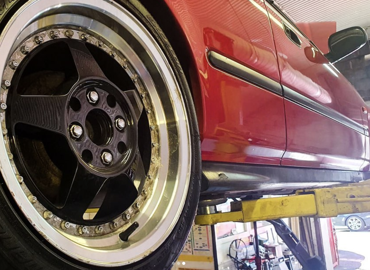 Close-up of a red sports car on the lift with custom split-rim alloy wheel