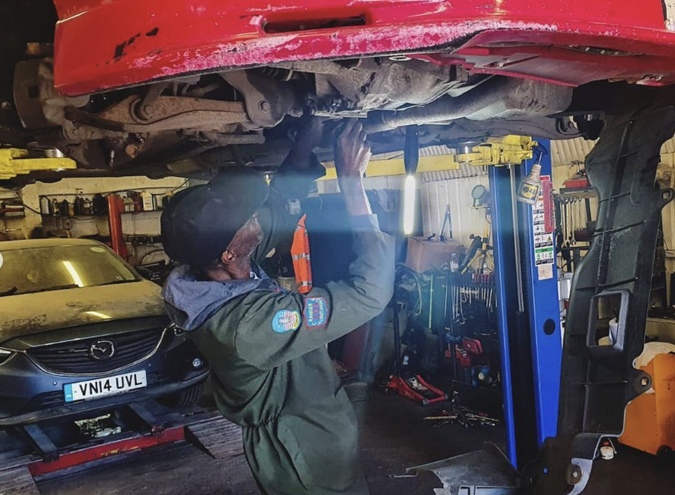 Mechanic working on the underside of a red car under good lighting