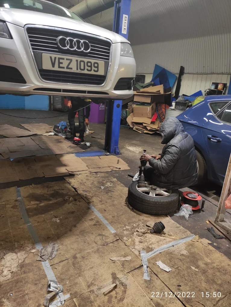 Audi on the two-post lift while a mechanic services a wheel hub